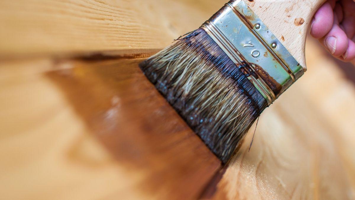 A paint brush applying a protective coat to wood