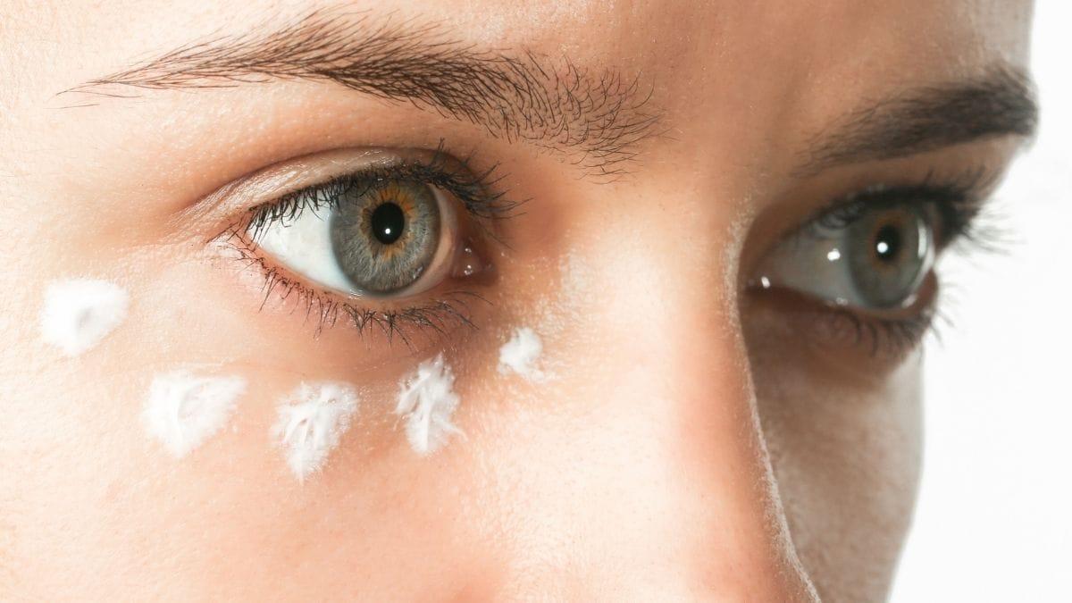 A woman dotting eye cream around her eyes before applying