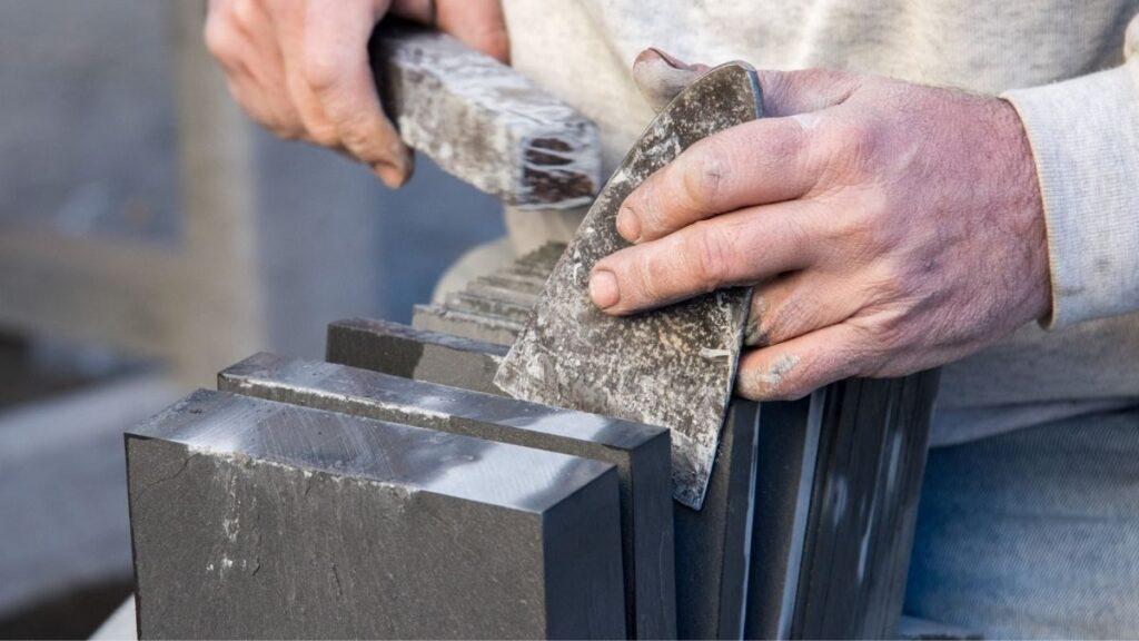 A craftsman using his hands to cut slate