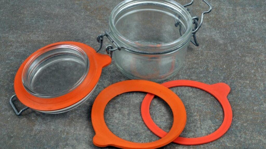 A glass canning jar with orange rubber seals