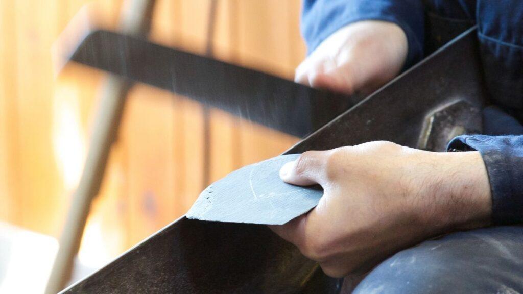 A worker using a slate cutter to make slate shapes