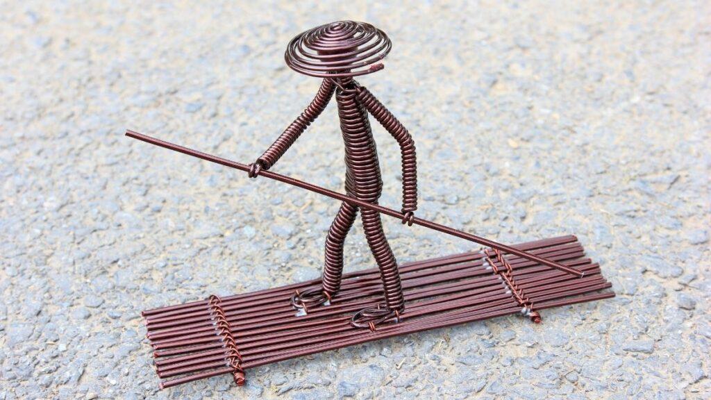 Copper wire bent and crafted into the shape of a man on a paddle boat