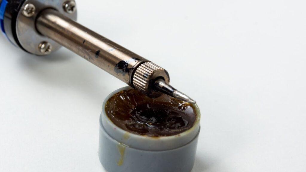 Hot soldering iron laying on a jar of resin