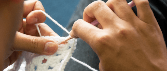 close up of hands crocheting corner of a square